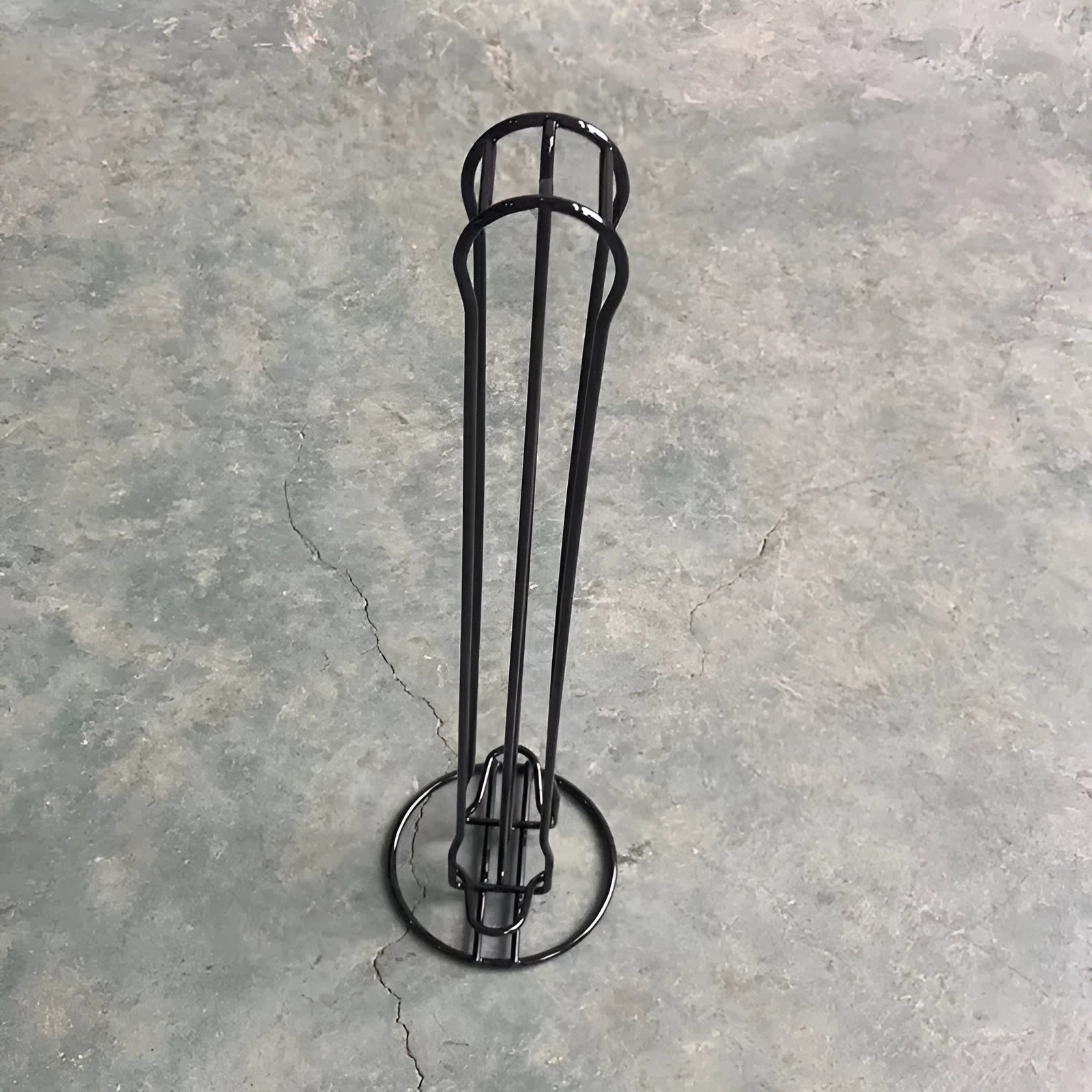 Black wrought iron coffee capsule storage rack holding 20 capsules on two shelves