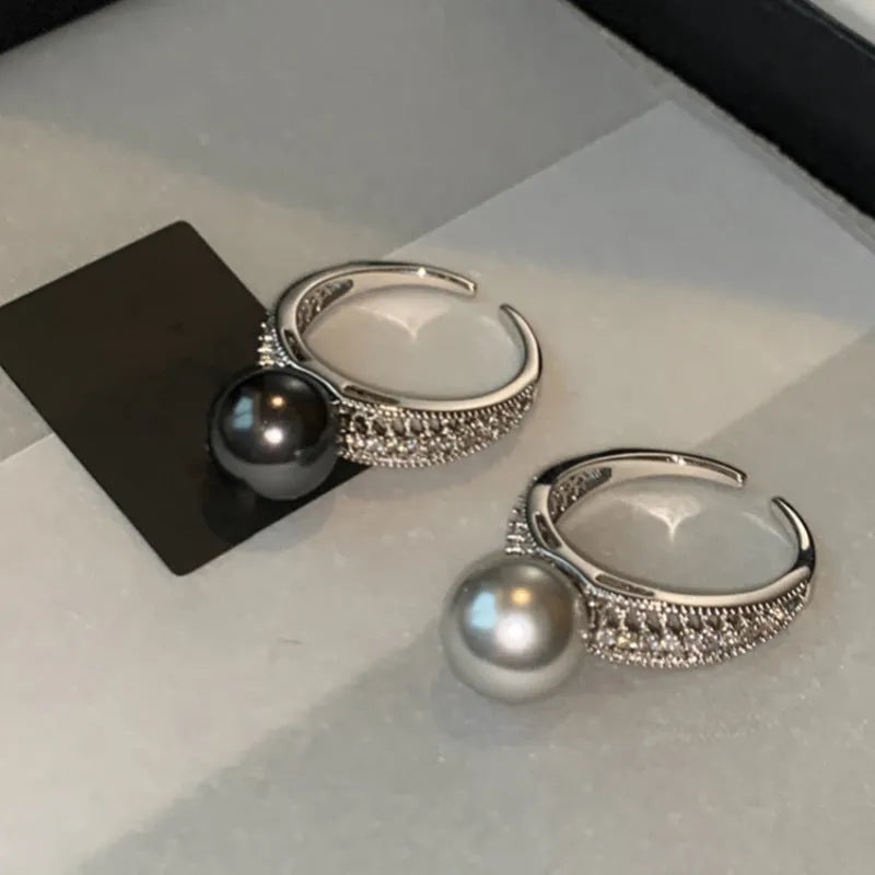 Adjustable black geometric pearl copper ring for women on a finger.