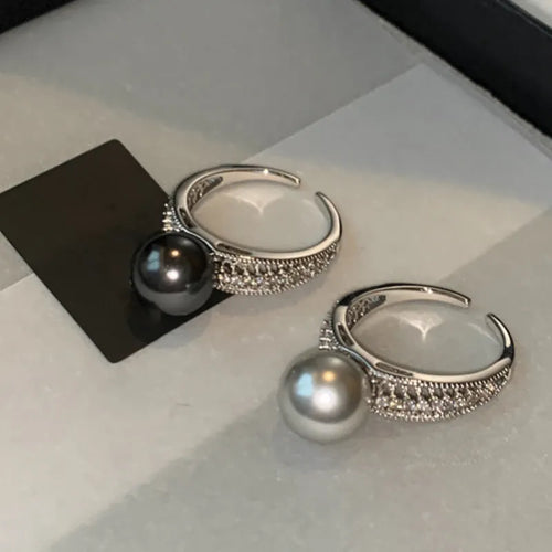 Adjustable black geometric pearl copper ring for women on a finger.
