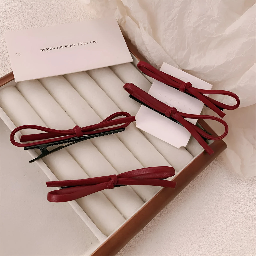 Wine red leather bow hair clip barrette on a white background.