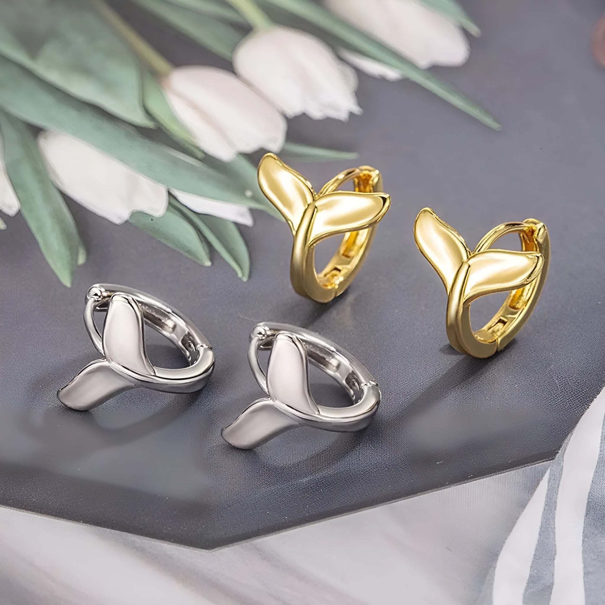 Women's fishtail design earrings in electroplated White Gold colour on a white background.