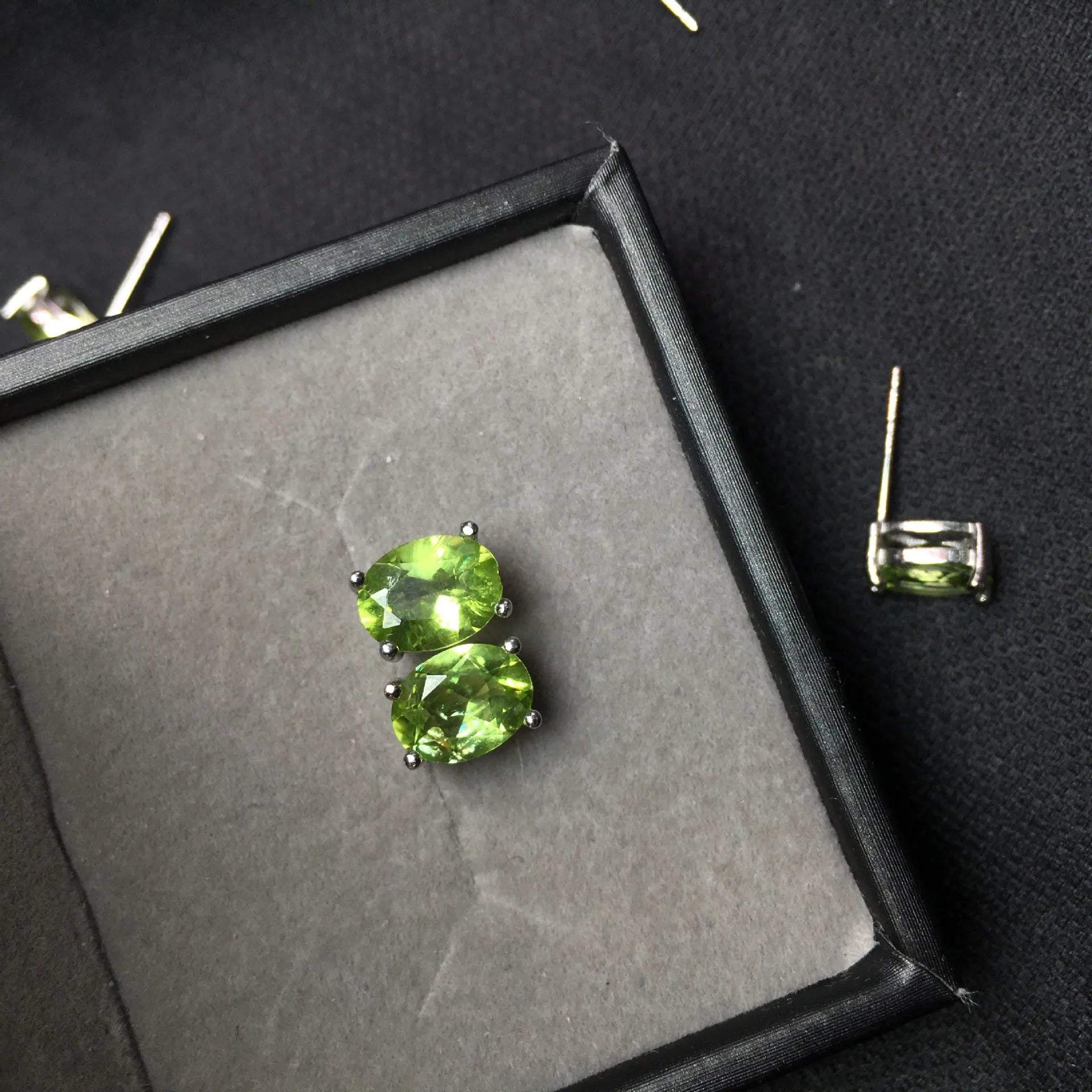 Natural grass green olivine faceted stud earrings in S925 silver settings on a white background.
