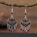 Close-up of long purple drop earrings with crystal fringe detail on an alloy setting.