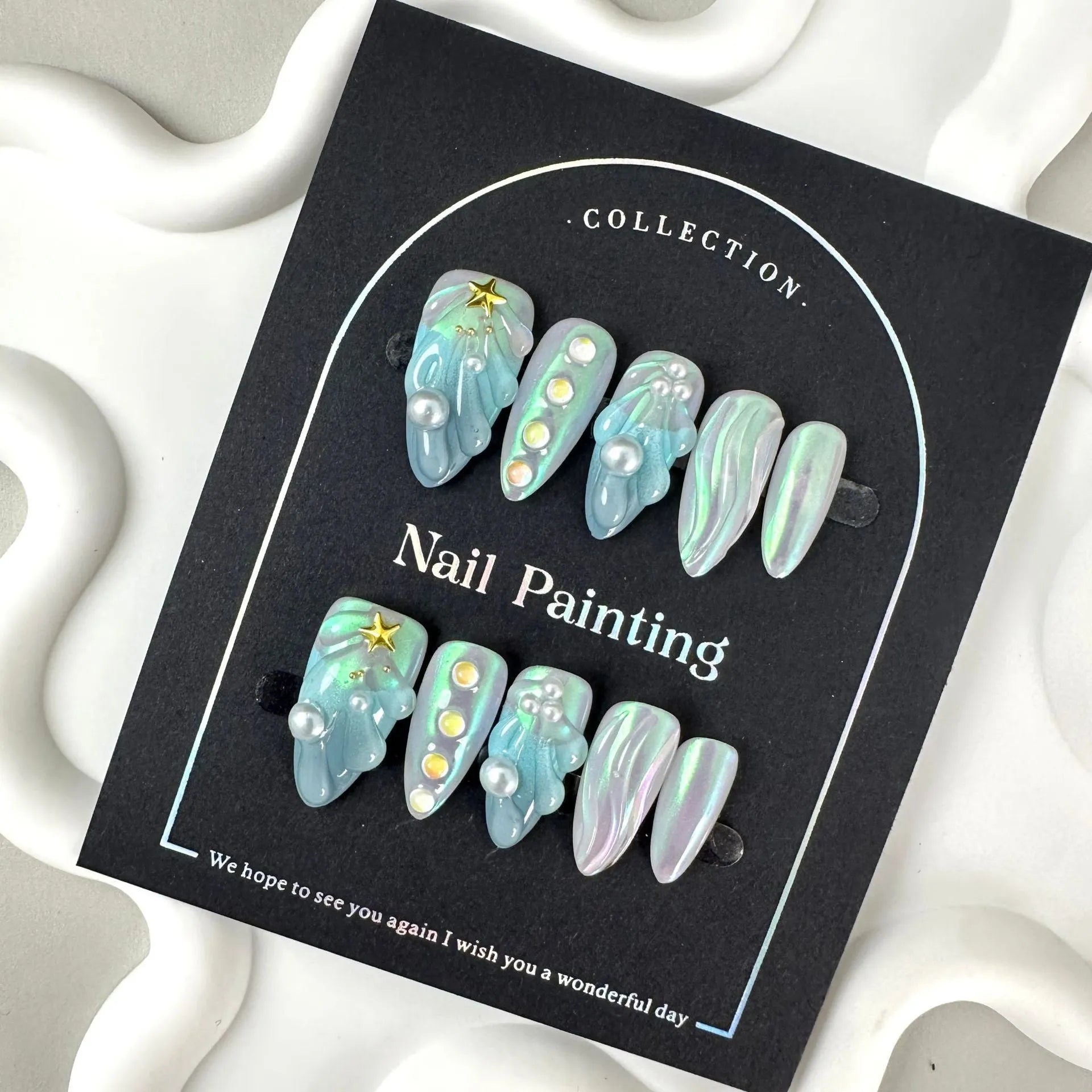 Blue plastic artificial nail tips set on a card, showing sizes labelled XS, S, M, and L.