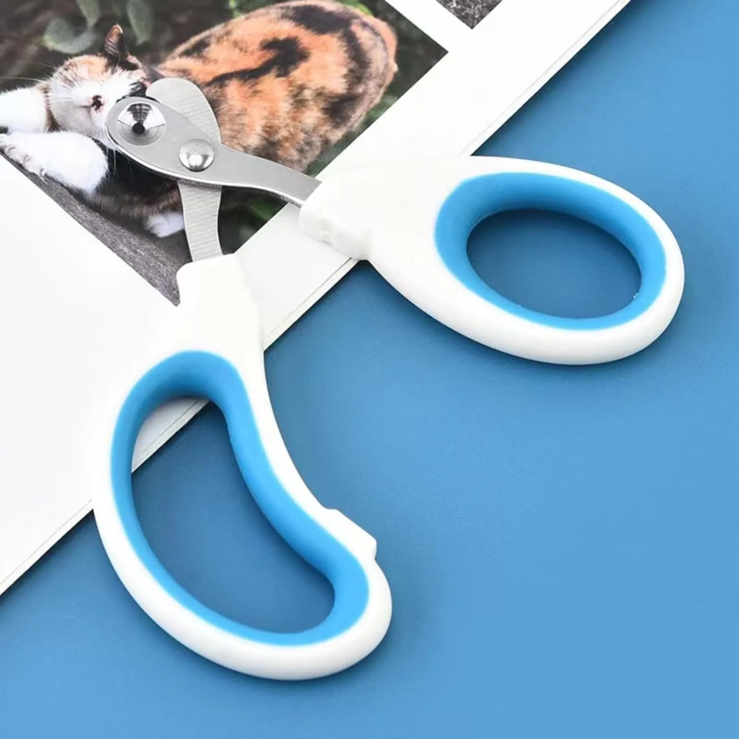 Blue pet nail clippers with circular cutting hole and non-slip handles on a white background.