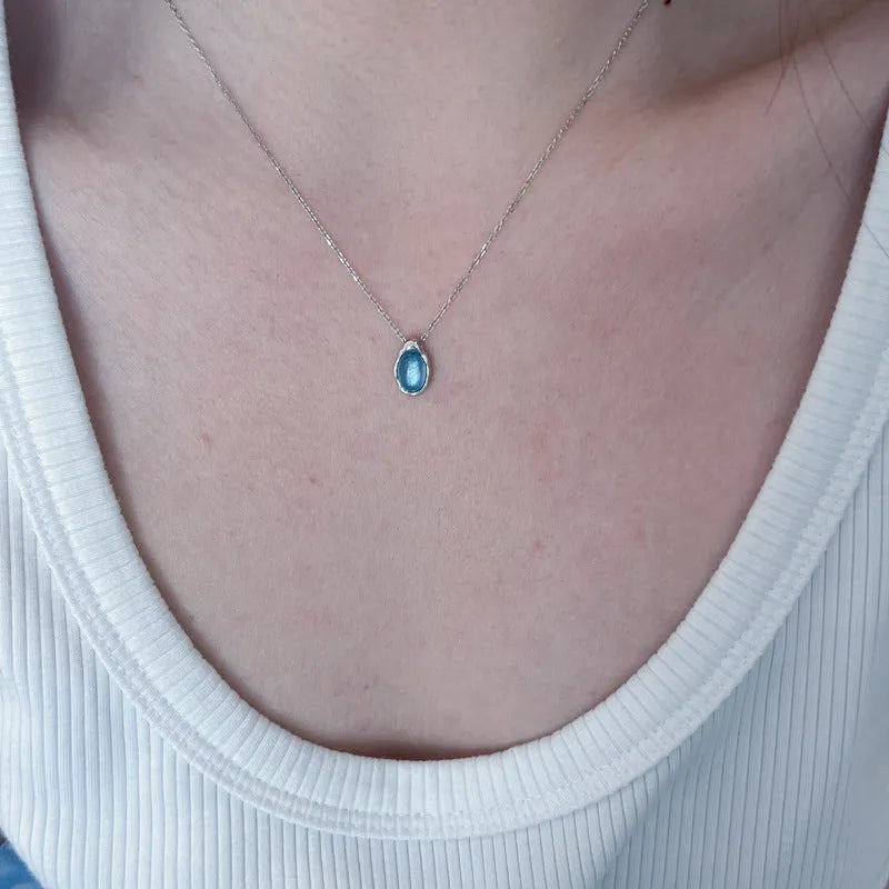 Navy blue geometric water drop pendant necklace with cross chain design on white background