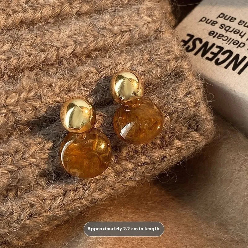 A set of three handmade geometric tassel earrings for women: Amber, round piece, and water drop styles.