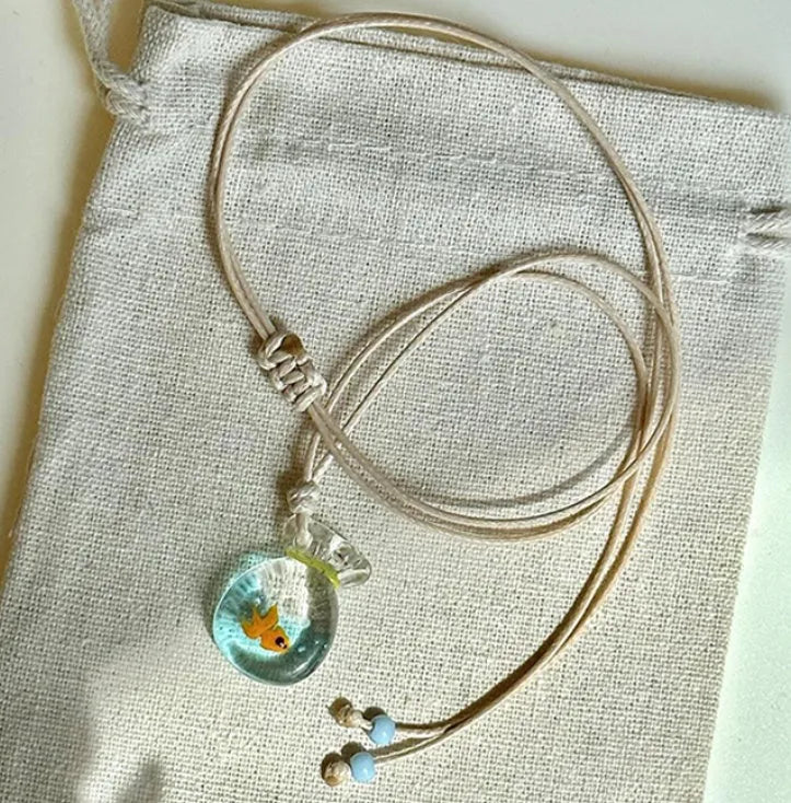 Women's necklace with coloured glaze joker pendant on a woven cotton and linen clavicle chain.