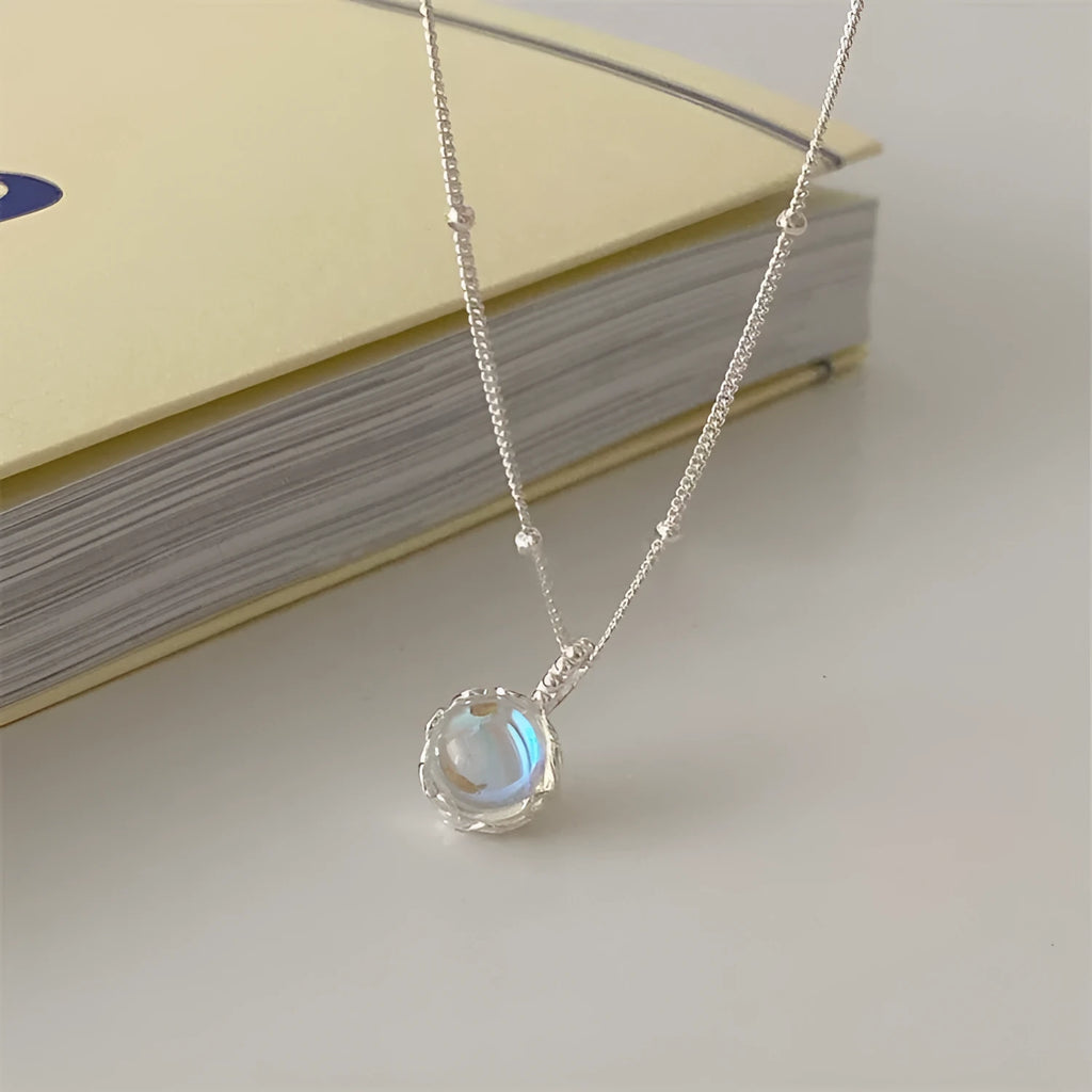Women's silver geometric pendant necklace with adjustable curb chain on grey background