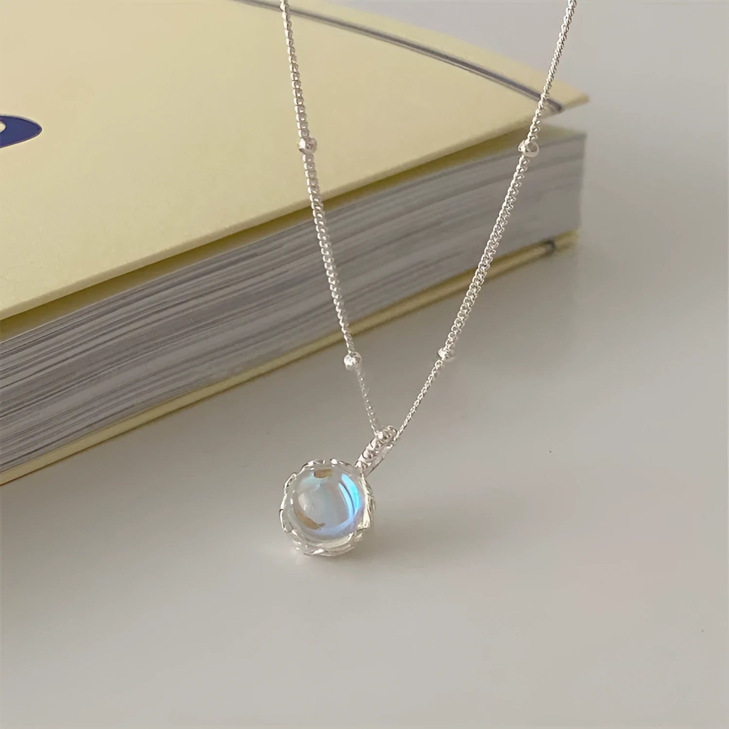 Women's silver geometric pendant necklace with adjustable curb chain on grey background