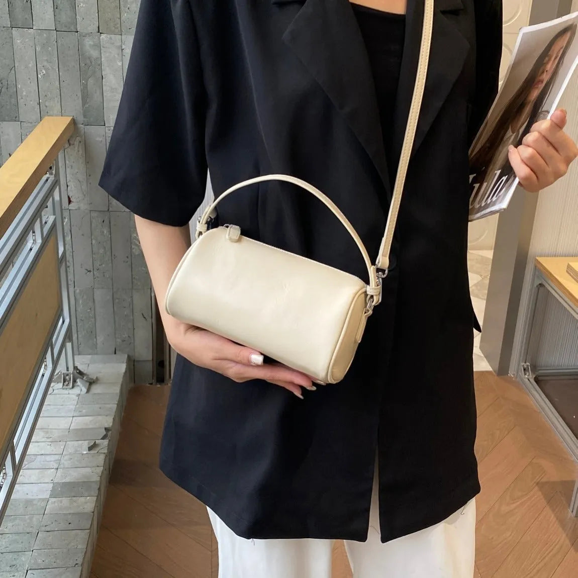 Vegetable-tanned leather cylindrical crossbody phone bag in black colour showing adjustable strap and visible stitching