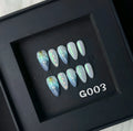Blue plastic artificial nail tips set on a card, showing sizes labelled XS, S, M, and L.