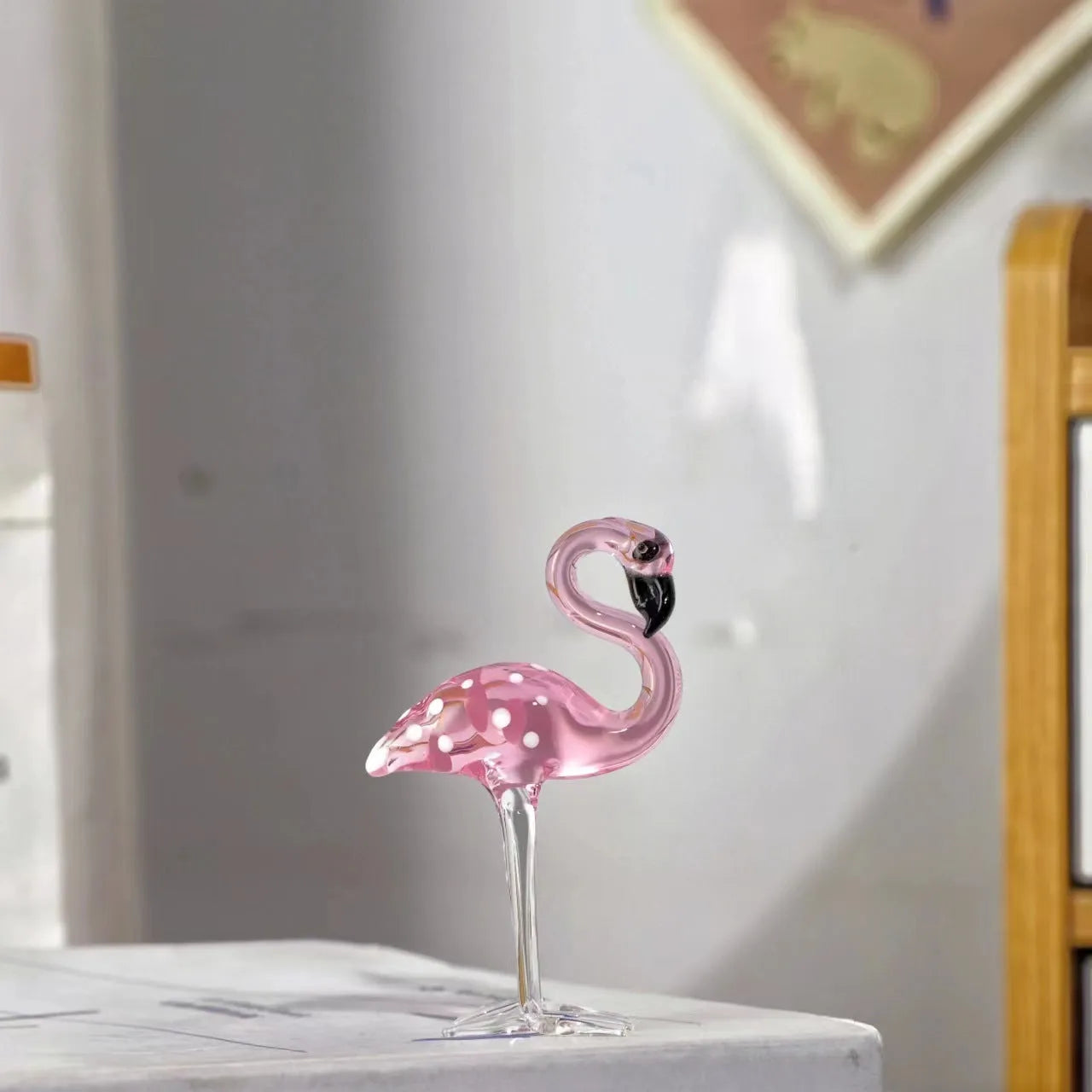 Clear crystal flamingo decorative sculpture with pink dots on a table.