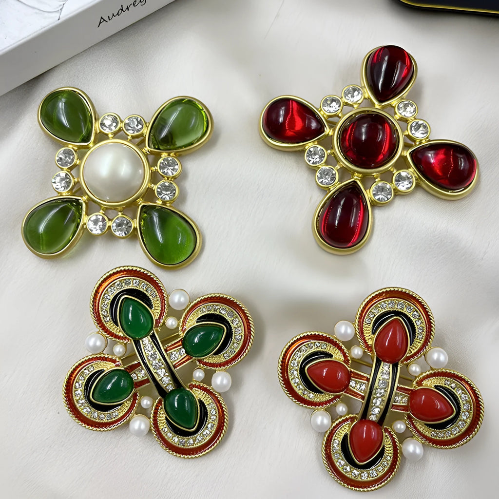 Vintage zinc alloy baroque cross brooch with crystal details on a dark fabric background.