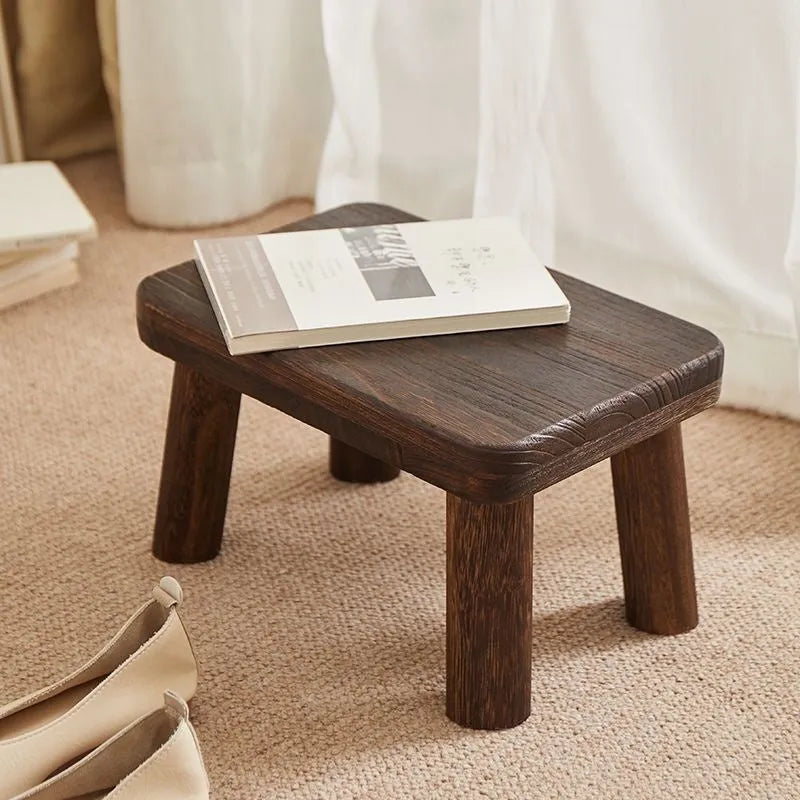 Solid wood household changing stool with a distressed finish for shoes in a living room.