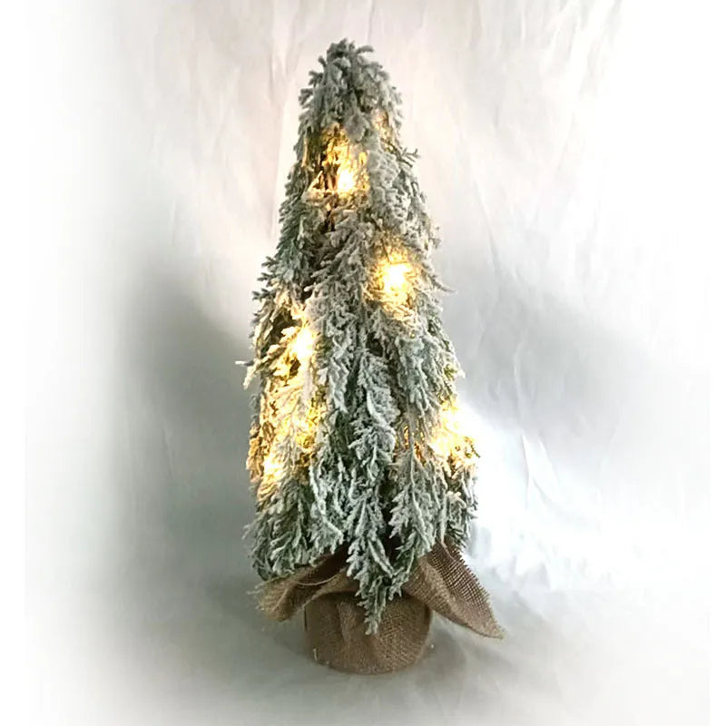 Small 24-inch white artificial Christmas tree with built-in LED lights and simulated snow sprayer on a desktop.