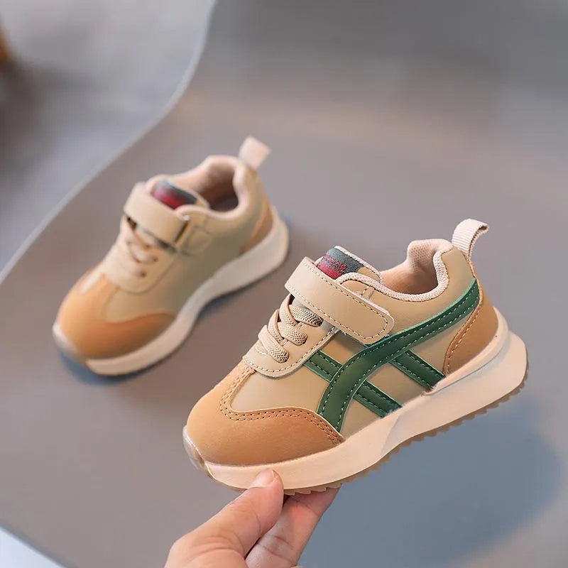 Children's white synthetic leather sneaker with Velcro strap and non-slip rubber sole.