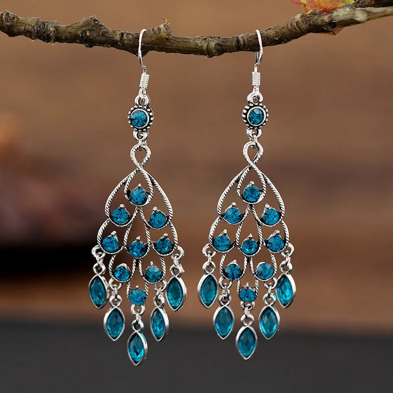 Close-up of long purple drop earrings with crystal fringe detail on an alloy setting.