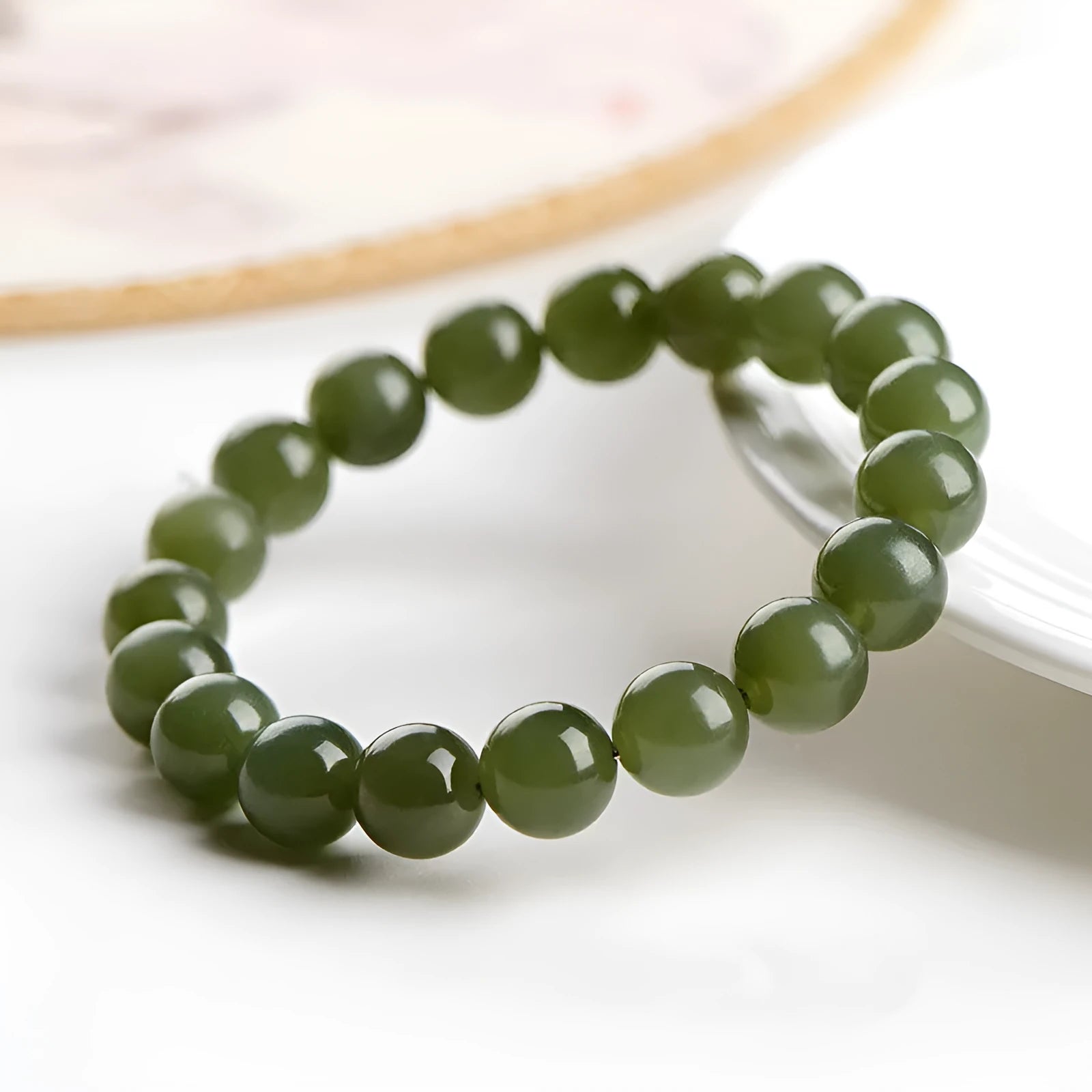 Polished Hetian Jade ball bead bracelet in deep clear water colour on a wrist.