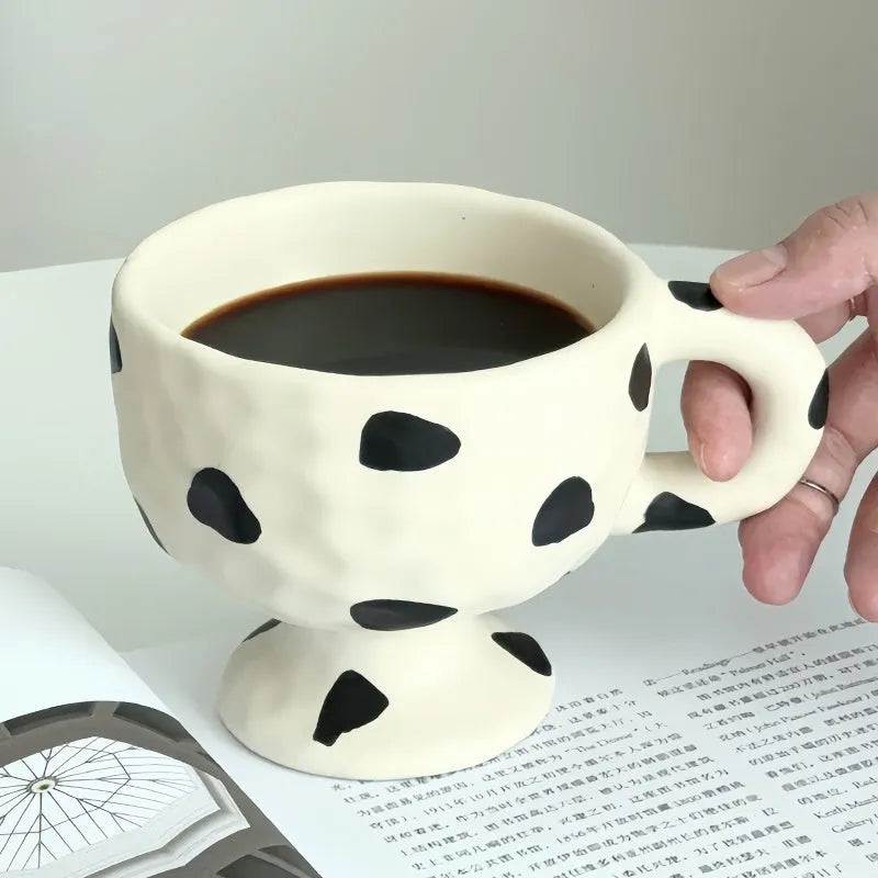 A handmade, irregularly shaped ceramic mug in a solid colour, shown on a table.
