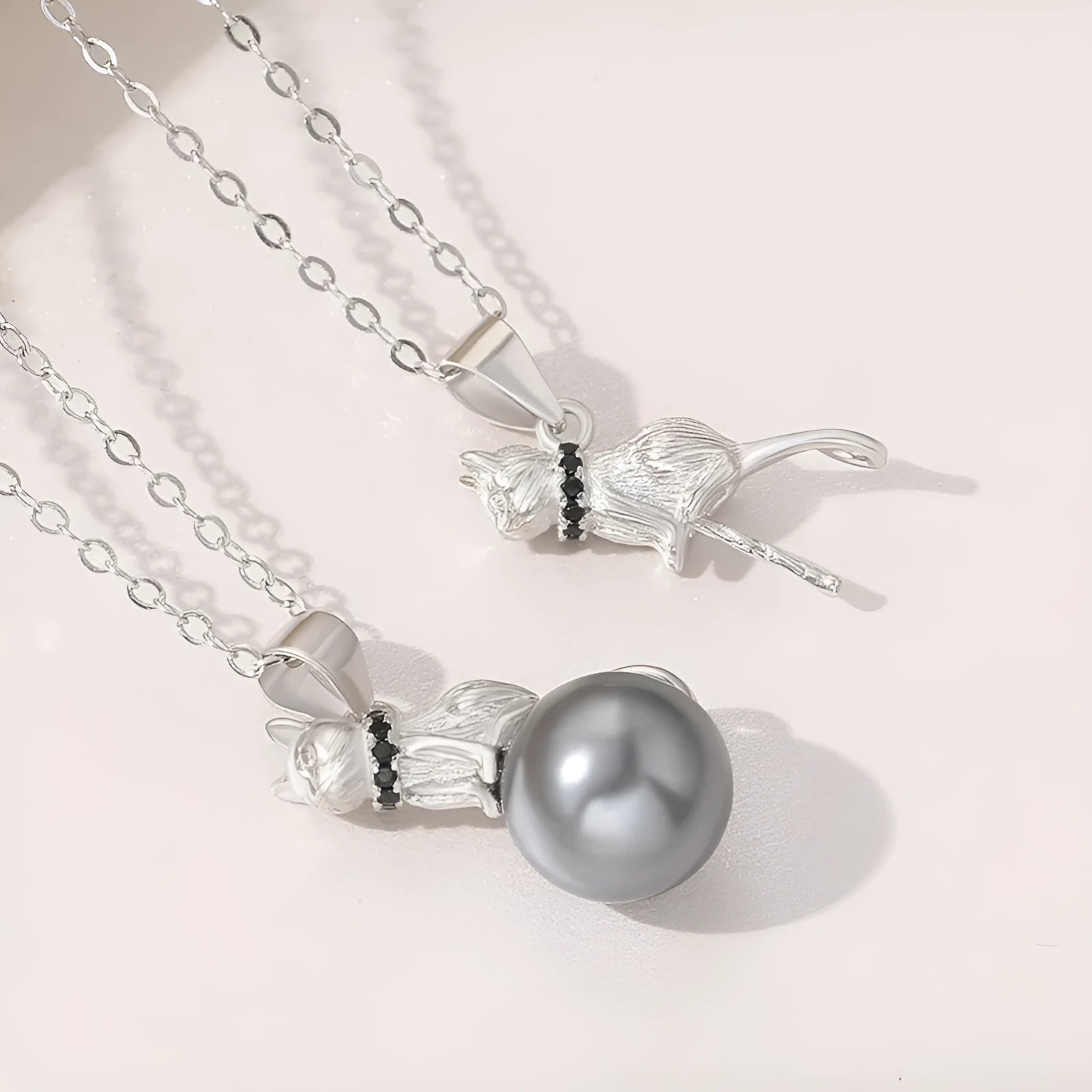 Close-up of a sterling silver cat pendant on a clavicle necklace chain.