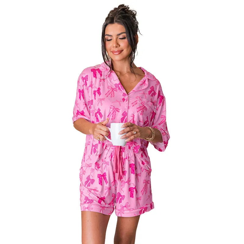 Pink women's pyjama set with bow print pattern showing top and trousers on hanger