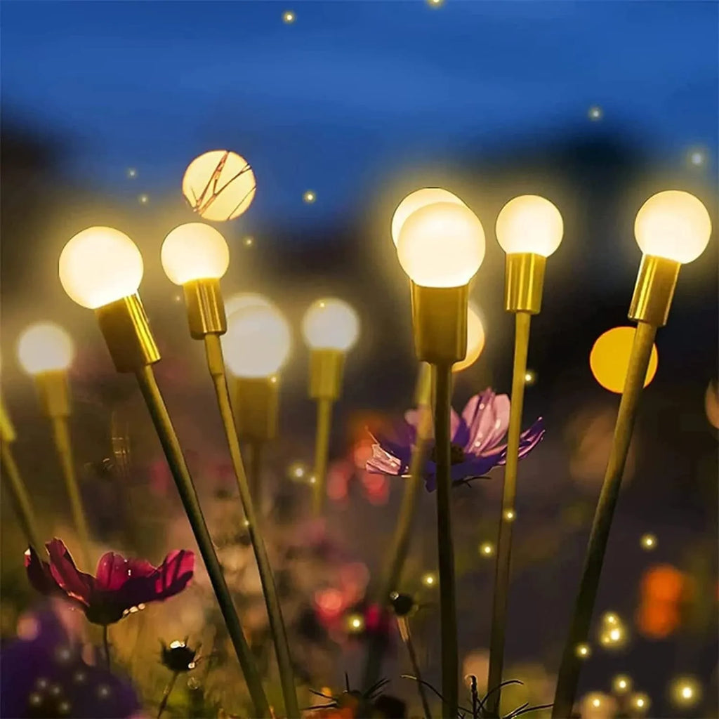 Solar-powered LED firefly garden spike light with stainless steel ground stake illuminated at dusk.