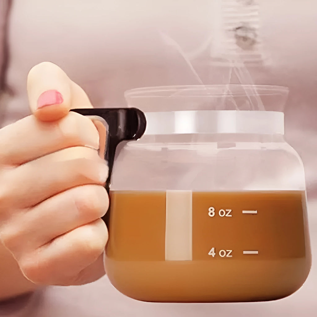 Transparent borosilicate glass coffee maker with black silicone cover on a kitchen counter.
