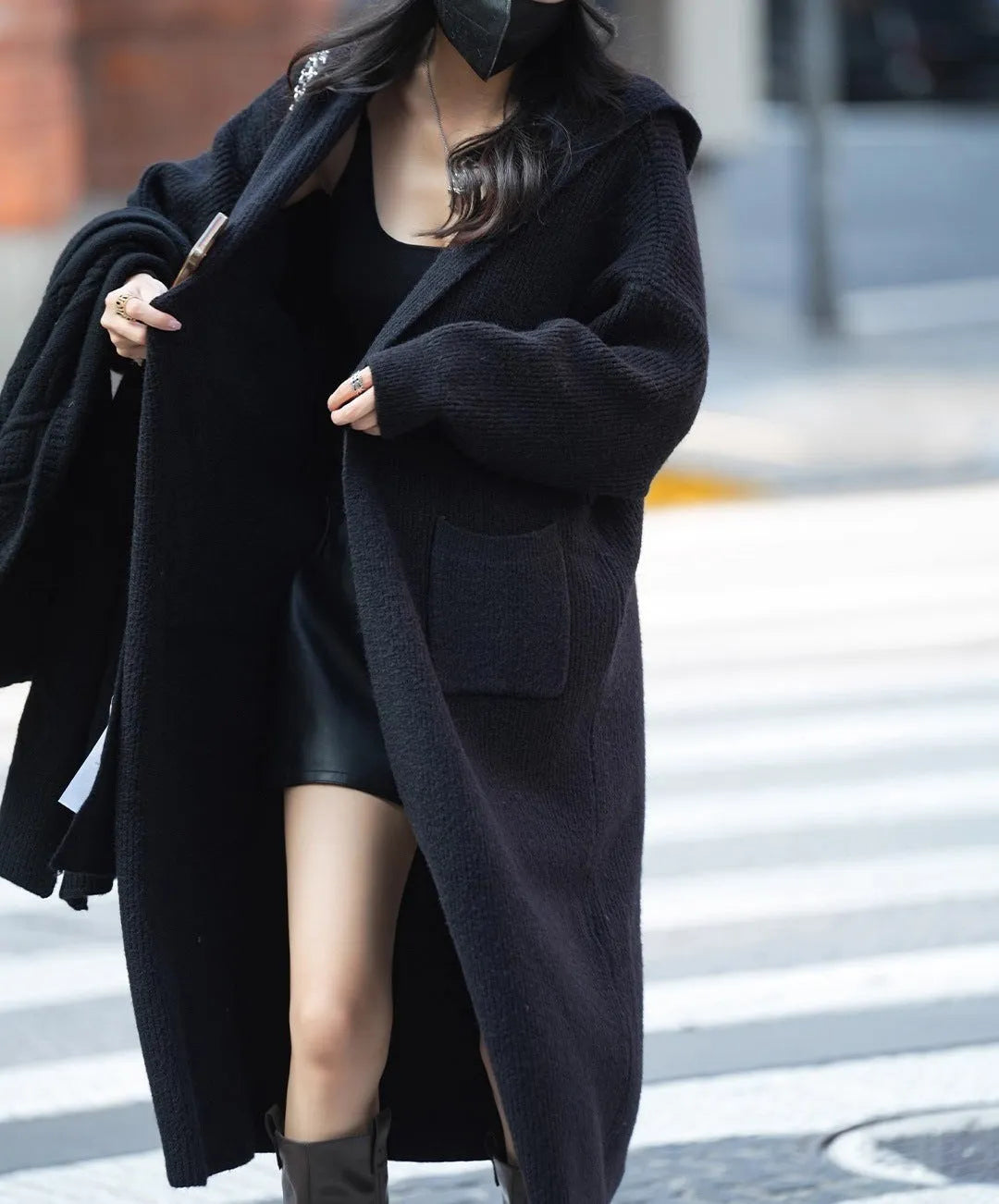 Long grey knitted women's cardigan with a hood, styled like a trench coat with long sleeves.
