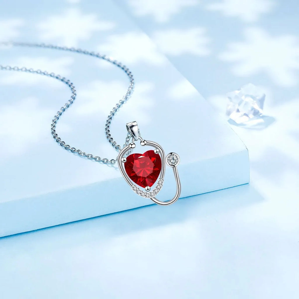 Red diamond copper necklace with stethoscope-shaped pendant featuring wings and cross detailing