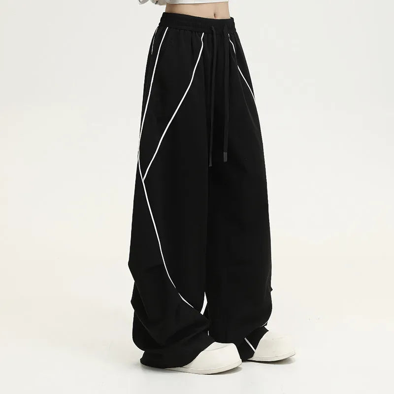 Black and white striped pleated wide-leg hip hop sports pants on a mannequin, showing loose fit and mid waist.