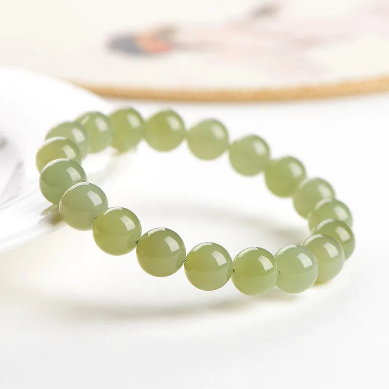 Polished Hetian Jade ball bead bracelet in deep clear water colour on a wrist.