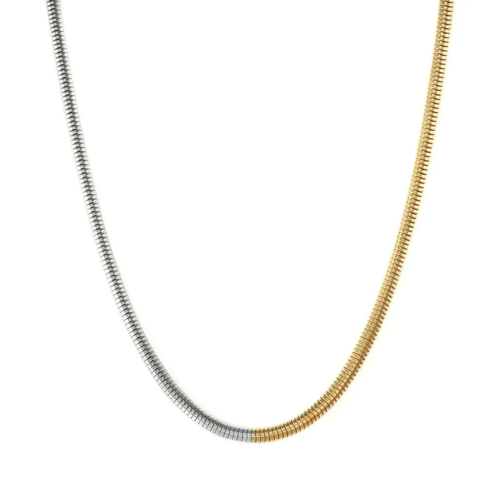 Close-up of a women's gold 3mm snake bone chain necklace with a geometric pendant.