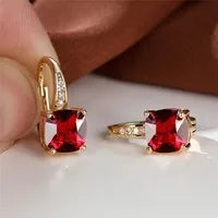 Geometric copper ear hook with round element and inlaid square zircon stone, shown in a golden colour.