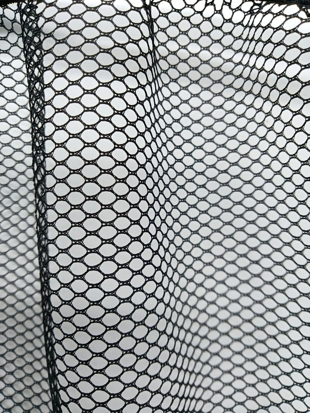 Black elastic polyester storage net stretched in a car boot, holding a water bottle and cloth.