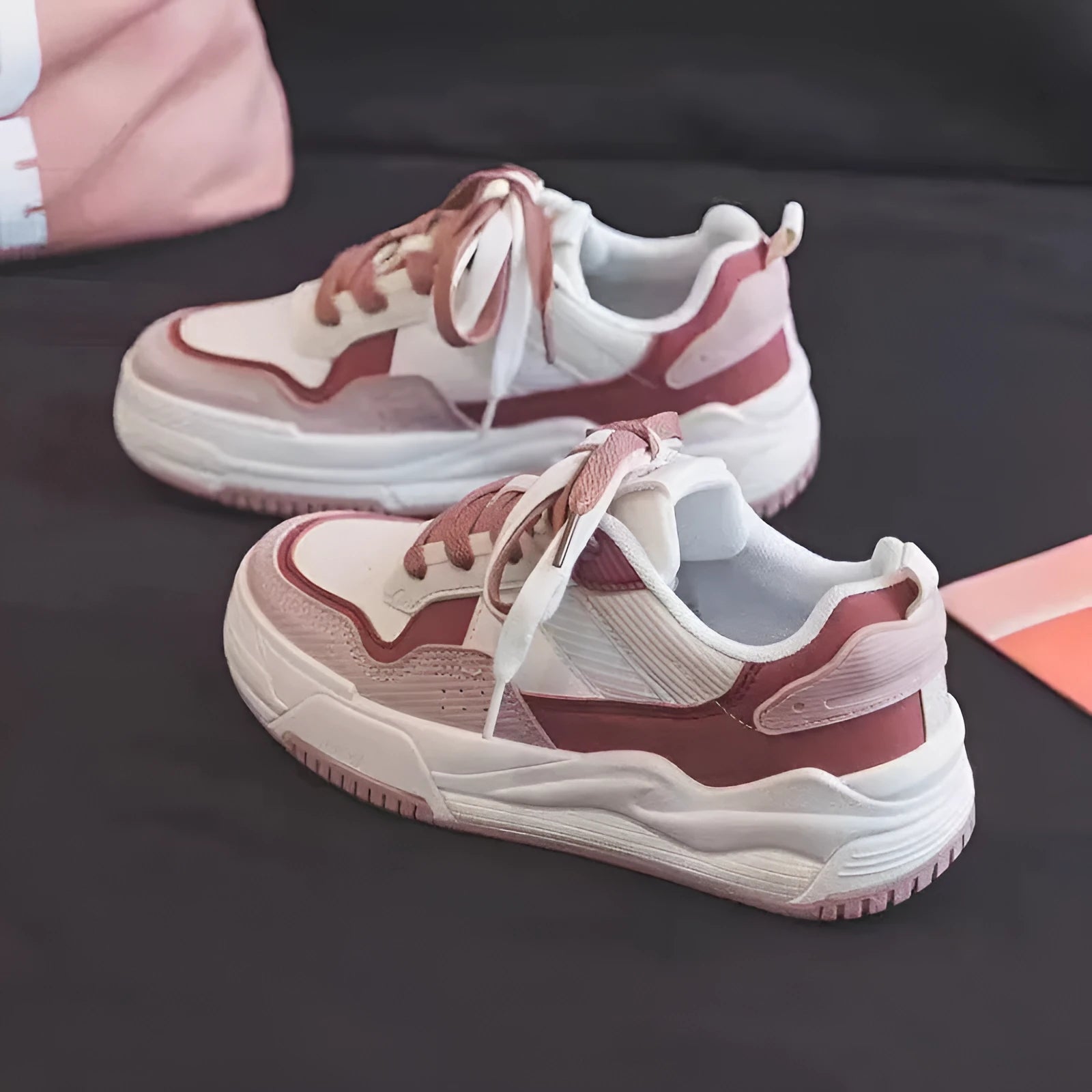Pink and white low-top height-increasing sneakers with rubber soles on a plain background.