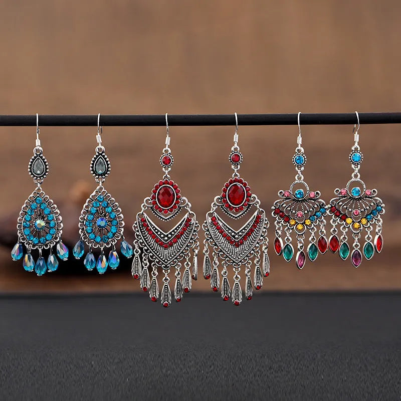 Close-up of long purple drop earrings with crystal fringe detail on an alloy setting.