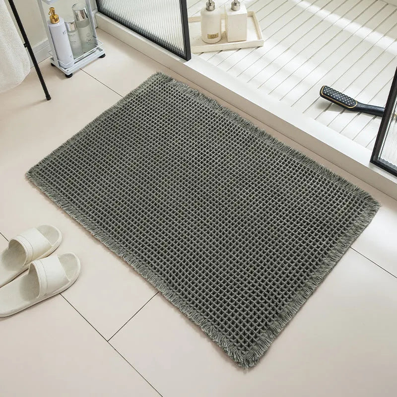 Square checkered polyester bathroom carpet on a tiled floor in a light grey colour.
