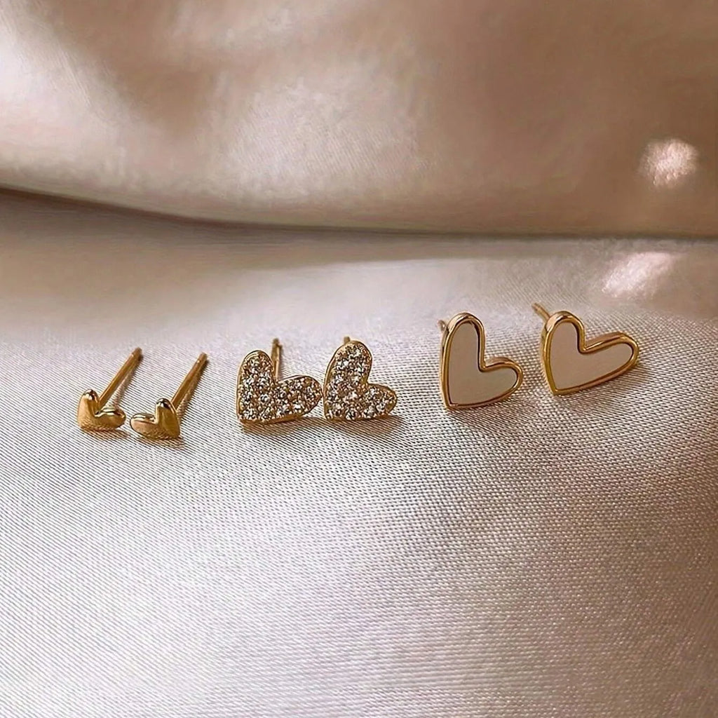 Three pairs of heart-shaped alloy earrings in gold, black, and pink with electroplated finish