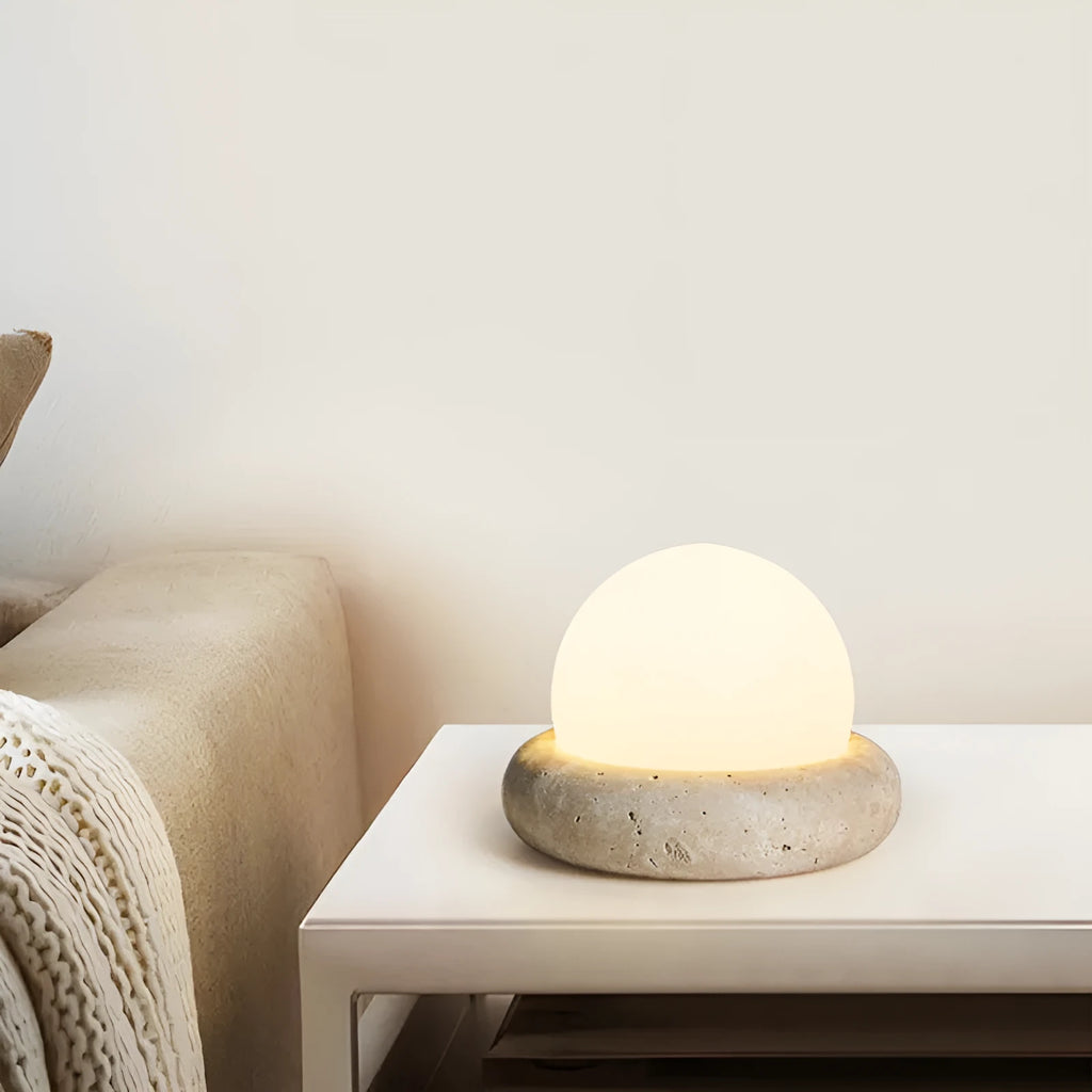 Cream-coloured round bedside night lamp with remote control on wooden table