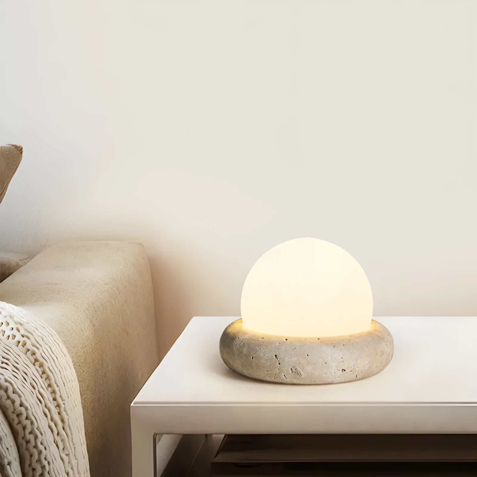 Cream-coloured round bedside night lamp with remote control on wooden table