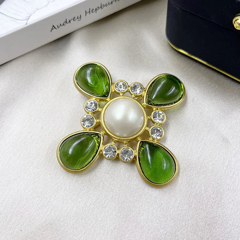 Vintage zinc alloy baroque cross brooch with crystal details on a dark fabric background.