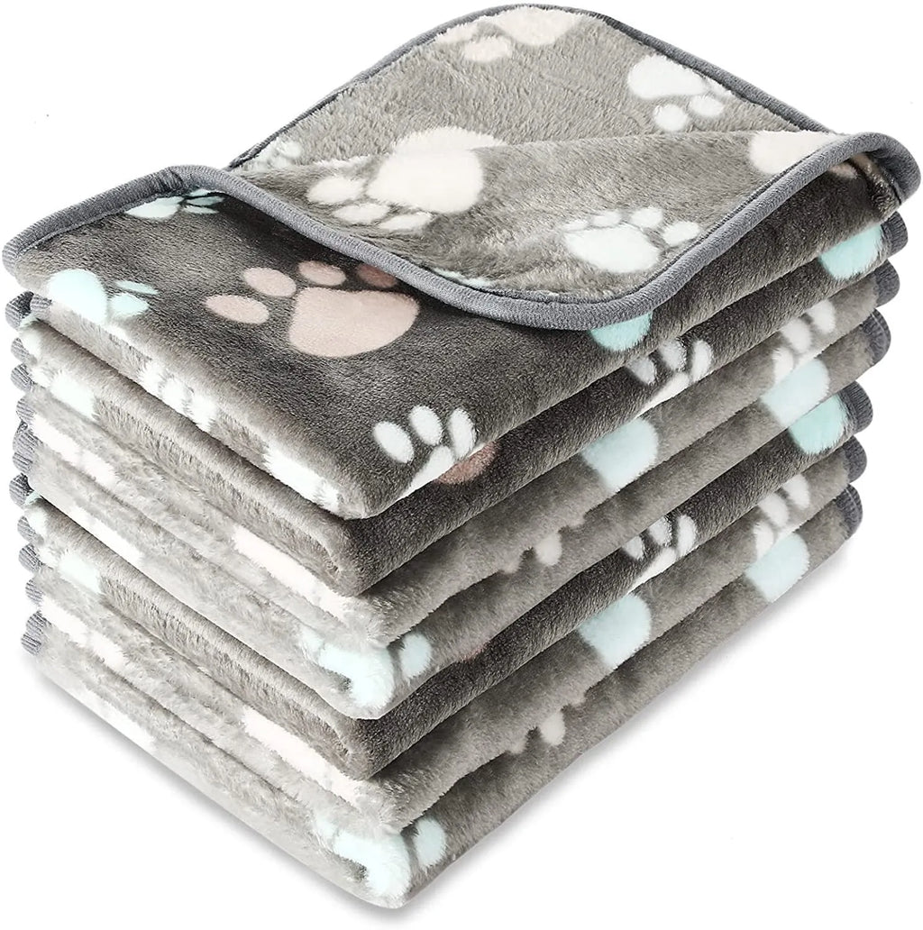 Cloth dog blanket with paw print design in beige, shown in a large size on a sofa.