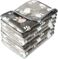 Cloth dog blanket with paw print design in beige, shown in a large size on a sofa.