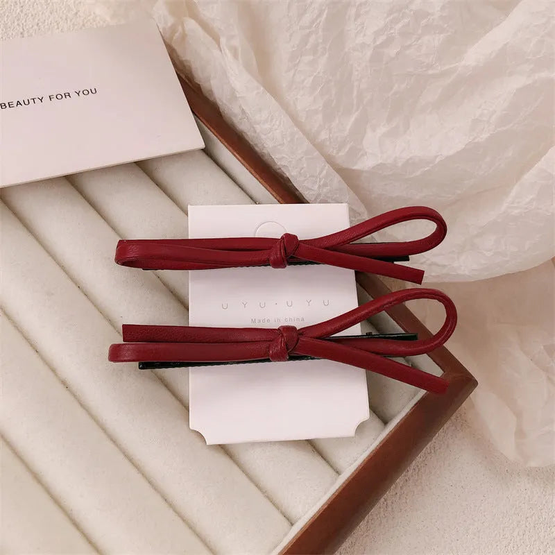 Wine red leather bow hair clip barrette on a white background.