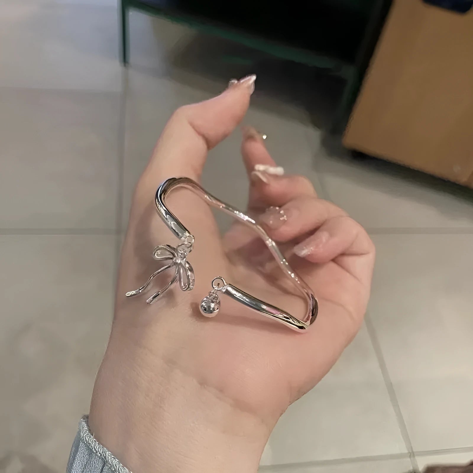 Silver adjustable bracelet with bow charm featuring bell opening detail