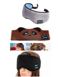 Black Bluetooth sleep eye mask with small integrated wireless earphones, shown in a relaxed position on a pillow.