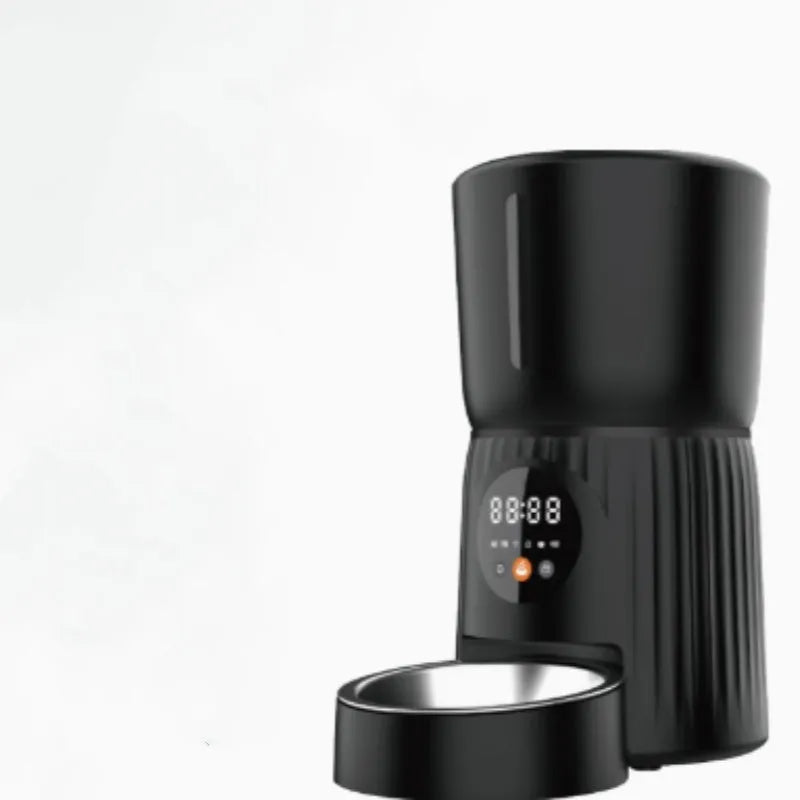 Black automatic pet feeder with digital display and food hopper on a countertop.