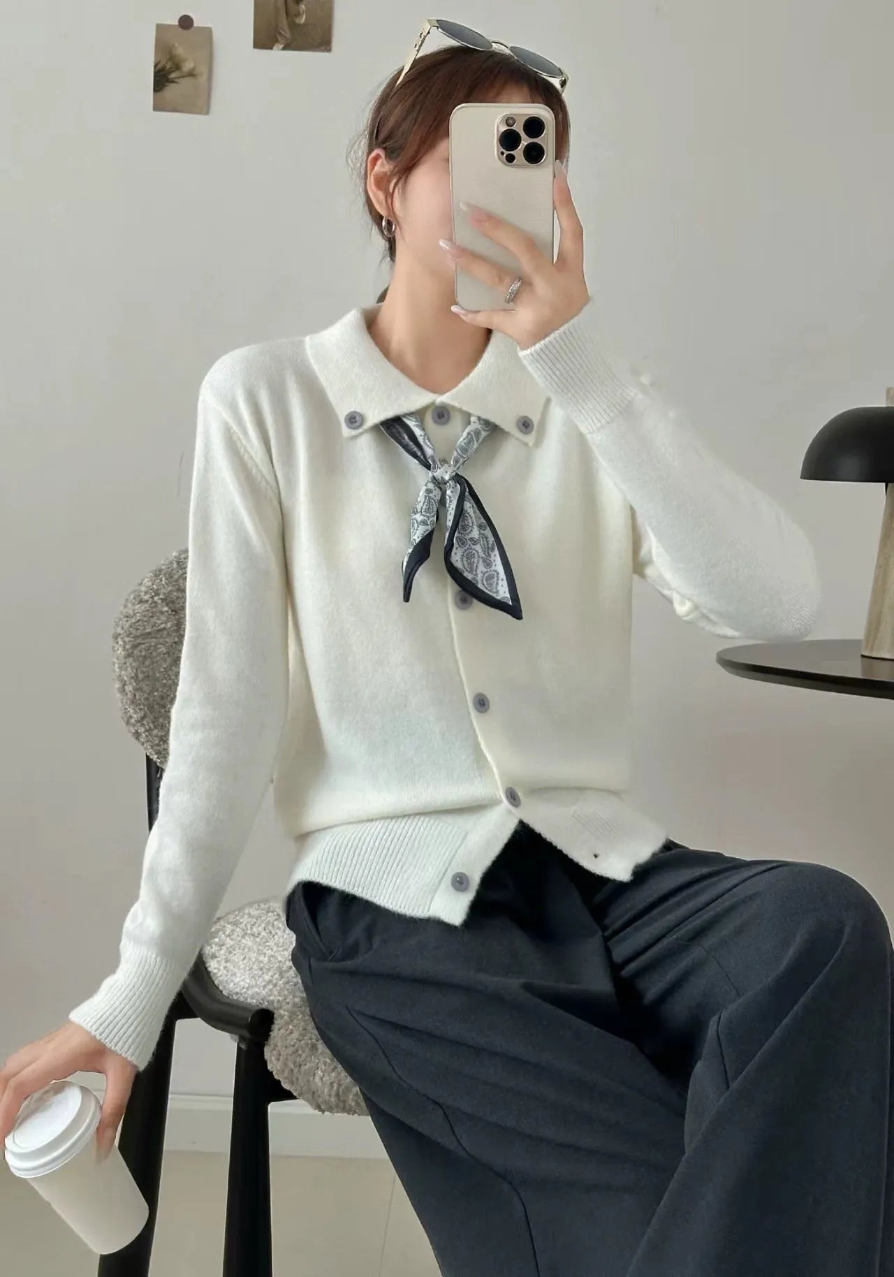 Beige acrylic cardigan with lapel scarf collar and splicing detail on a hanger.
