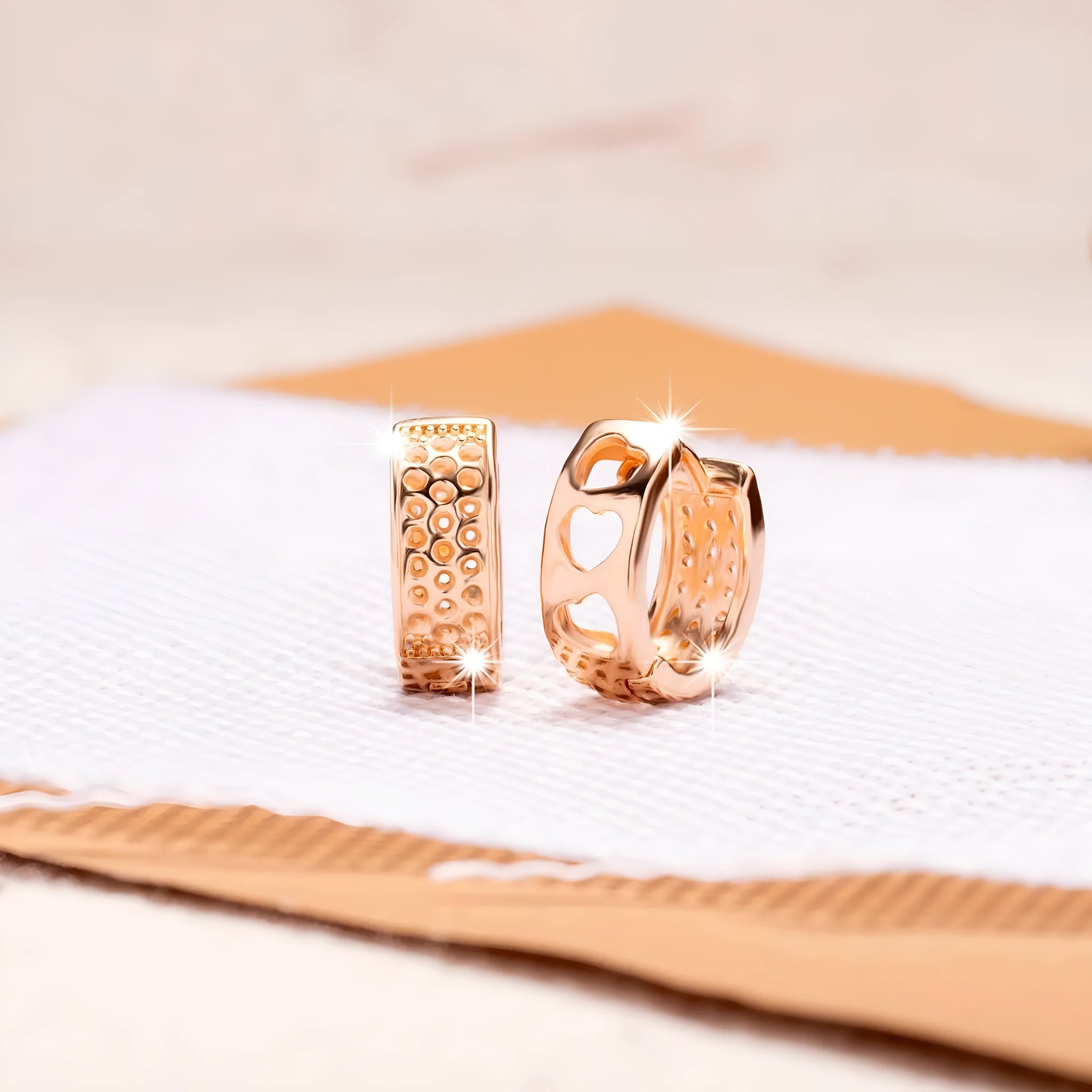 A pair of rose gold women's earrings with three hollowed-out heart shapes in a circular design.